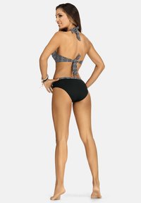 Czarny i biały biustonosz bikini w wzory z odkrytymi ramionami i zawiązywaniem na karku. Gładkie czarne, wysokie majtki bikini. Gładka tekstura.