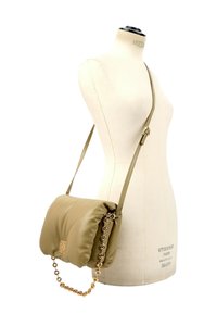 Sac bandoulière en cuir beige avec chaîne dorée et bandoulière ajustable, présenté sur un torse de mannequin blanc.