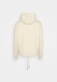 Sweat à capuche couleur crème avec capuche à cordon, poignets et taille côtelés. Tissu doux avec une texture lisse et coupe décontractée.