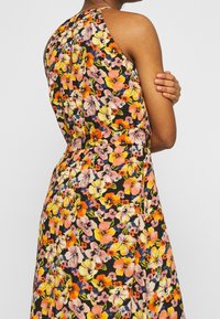 Vestido floral con un fondo negro y flores vibrantes en tonos rosa, naranja y amarillo. Incluye tirantes de estilo tank y una cintura ajustada.