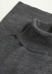 Gros plan sur un pull à col roulé en tricot gris foncé plié, montrant la texture et le col côtelé sur un fond clair.