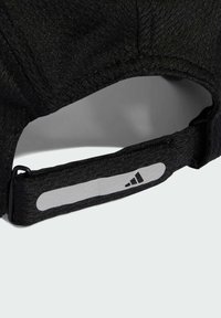 Gorra negra con un tejido texturizado, correa ajustable y detalle del logo reflectante de Adidas en la correa. Cuenta con un visera curva.