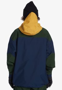 Colorful jacket featuring yellow hood, dark blue body, and green accents. Textured fabric with elastic cuffs and gloves.