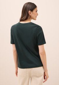 Camiseta de color verde oscuro, de manga corta y con cuello redondo. Material de algodón, textura suave, corte recto, sin patrones ni embellishments visibles.