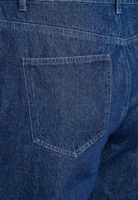 Temno modri jeans iz denima z zadnjim žepom, ki se ponaša s subtilno teksturo in ojačanim šivom ob robovih za večjo vzdržljivost.