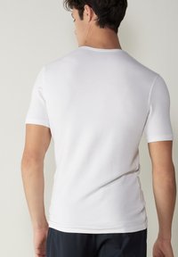 T-shirt blanc à manches courtes en tissu doux et lisse. Design ajusté avec un col rond et une légère élasticité.