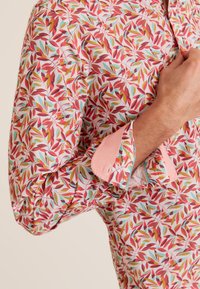 Korte mouwen blouse met een bloemenpatroon in roze, rood, groen en blauw. Kenmerkt een contrasterende roze manchette en lichtgewicht katoen.