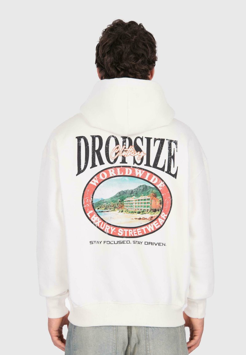 Person in einem weißen Hoodie mit einem bunten Strand- und Bergmotiv sowie dem Text "DROPSIZE Clothing Worldwide Luxury Streetwear" auf dem Rücken.