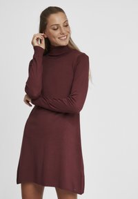 Robe turtleneck bordeaux à manches longues, à coupe d�écontractée, avec des fentes sur les côtés. Texture douce, col et poignets côtelés, avec un petit accent métallique.
