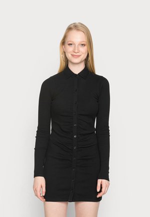 Vestido preto, de manga longa e com botões, com colarinho, apresentando uma silhueta ajustada e textura pregueada na parte frontal.