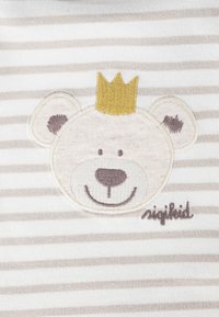 Un tessuto a strisce beige e bianco presenta un volto di orso ricamato con una corona gialla e accenti marroni, insieme a una cucitura "sigikid".