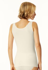 Canottiera senza maniche beige realizzata in tessuto morbido, con scollatura arrotondata e superficie liscia, caratterizzata da una silhouette aderente.