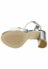 Sandale à talon haut argentée avec une texture reptilienne, une lanière de cheville ajustable et un talon carré. Semelle extérieure translucide avec un motif texturé.