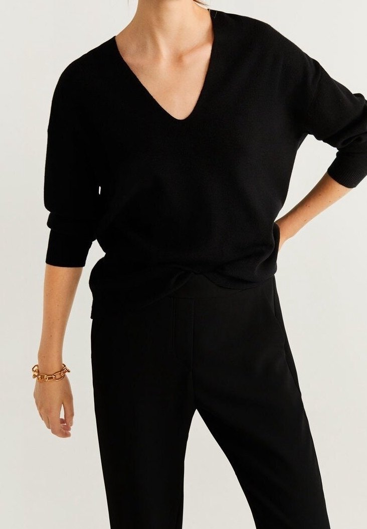 Black, soft knit sweater with a deep V-neck and three-quarter sleeves, paired with black tailored pants. Simple, minimal design.
