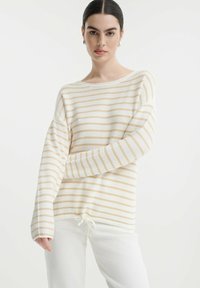 Maglione leggero a righe in crema e beige, con vestibilità morbida, scollo rotondo e orlo con cordoncino. Morbido al tatto, con maniche lunghe.
