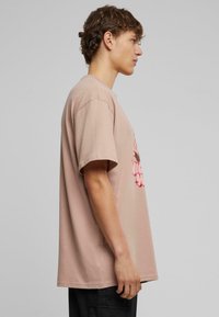 Kortærmet, lyserød bomulds T-shirt med afslappet pasform, prydet med et grafisk design i nuancer af pink og sort på forsiden.