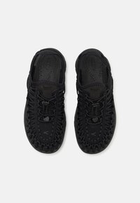 Scarpe nere open-toe con una tomaia in tessuto intrecciato, caratterizzate da un design leggero, lacci elastici e una suola in gomma sagomata.