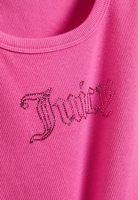 Ροζ υφασμα με ραβδώσεις με τη λέξη "TOMMY" γραμμένη σε σκοτεινό ροζ σχέδιο από στρας και μια καρδιά που διακοσμεί τη δεξιά πλευρά του κειμένου.