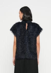 Černý texturovaný top z chlupatého, chlupatého materiálu, s krátkými rukávy a průstřihem na zádech. Lem končí v pase.