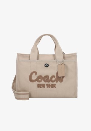 Saco de lona bege com o texto em bordado castanho "Coach New York", alças curtas, alça de ombro destacável e uma pequena etiqueta presa.