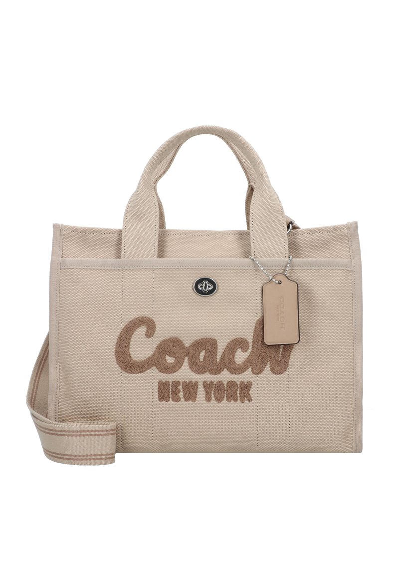 Beige canvas tote bag with brown embroidered "Coach New York" text, short handles, detachable shoulder strap, and small tag attached.