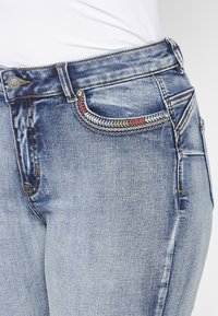 Blaue Denim-Jeans mit klassischem Design, leichtem Verblassen, Vordertasche mit dekorativer Naht und silberfarbener Hardware.