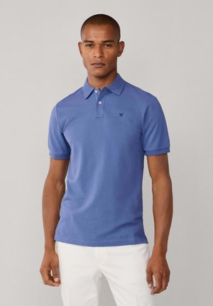 Polo de manga corta azul con cuello y tres botones. Presenta un sutil bordado de logo y un tejido de algodón texturizado.