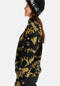 Felpa in pile nera con motivo floreale giallo e dettagli in rosa, dotata di colletto con mezza zip e logo Roxy sulla manica sinistra.