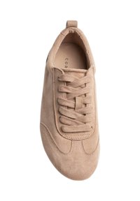 Baskets en daim beige avec une boîte à orteils arrondie, des lacets plats, et un design latéral sans coutures présentant des détails de couture subtils.