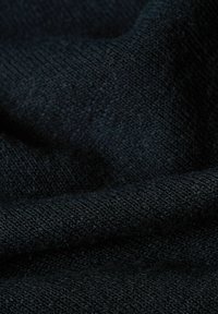 Tessuto nero a maglia che mostra una superficie liscia con una trama fine e uniforme. Il colore è un nero profondo, con sfumature sottili visibili nelle pieghe.