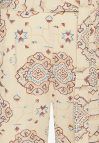 Patterned fabric featuring geometric designs in red and blue on a cream background. Includes a tied belt detail.