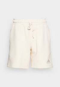 Kremowe bawełniane szorty z elastycznym pasem i sznurkiem do wiązania, wyposażone w boczne kieszenie oraz małe haftowane logo na nogawce.