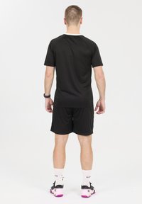 Mustat urheilupaidat ja shortsit kevyestä, hengittävästä materiaalista. Paidassa on pyöreä kaulus ja lyhyet hihat. Ei kuvioita tai yksityiskohtia.