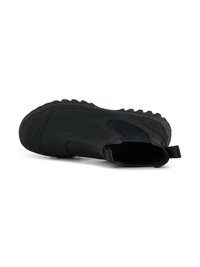 Scarpa nera senza lacci con tomaia liscia e opaca, pannelli elastici laterali e suola in gomma robusta con profonde scanalature per una migliore aderenza.