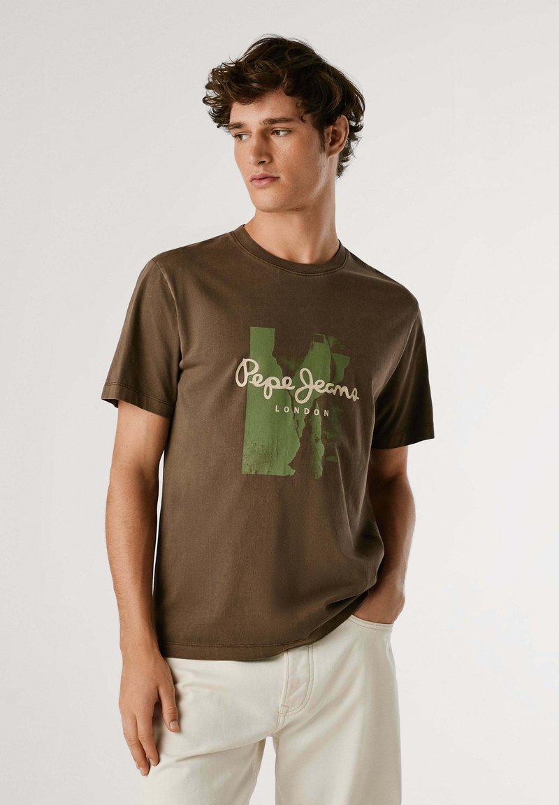 Camiseta de algodón marrón con un diseño gráfico verde y el texto "Pepe Jeans London". Cuello redondo y mangas cortas, con un ajuste relajado.
