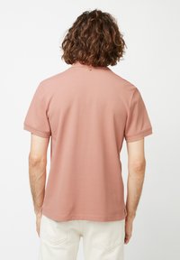 Polo a maniche corte in morbido tessuto rosa chiaro con colletto, caratterizzato da un dettaglio con un singolo bottone al collo e una vestibilità rilassata.