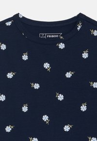 Navyblauwe t-shirt met een ronde hals, voorzien van verspreide lichtblauwe bloemenprints en groene stelen op een zachte, lichte stof. Etiket zichtbaar.