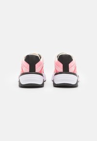 Chaussures de sport roses et noires avec une tige en mesh texturé, une semelle intermédiaire blanche coussinée et une semelle extérieure en caoutchouc noir résistante.