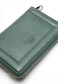Groene leren ritstassen met een textuurafwerking, voorzien van een kaarthouder aan de voorkant en gouden ritshardware. Subtiel reliëf logo detail.