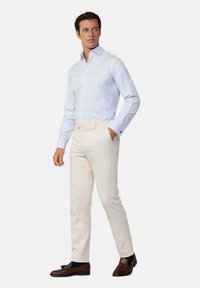 Lichtblauw geruit overhemd met knoopsluiting en crème slim-fit broek en bruine loafers. Het overhemd heeft contrasterende donkere manchetten.