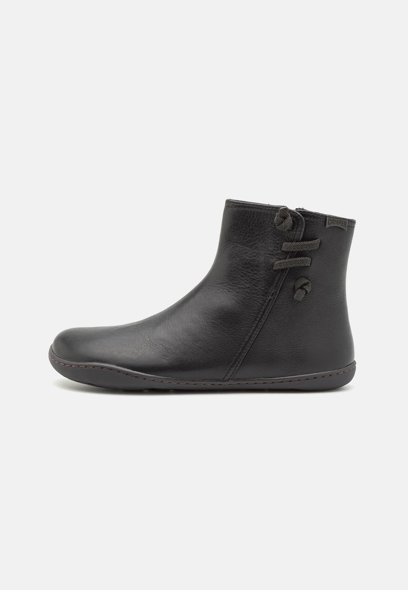 Bottine noire en cuir avec bout rond, semelle plate, fermeture éclair latérale et lacets décoratifs sur le côté extérieur.
