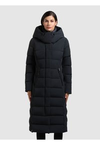 Lungo cappotto imbottito nero con cappuccio, caratterizzato da un design trapuntato, tasche laterali con zip e una silhouette slanciata. Realizzato in materiale isolante.