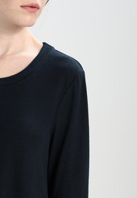 Námořnická modrá, dlouhý rukáv, top z jemného pleteného materiálu s kulatým výstřihem a jemnou texturou na povrchu oděvu.