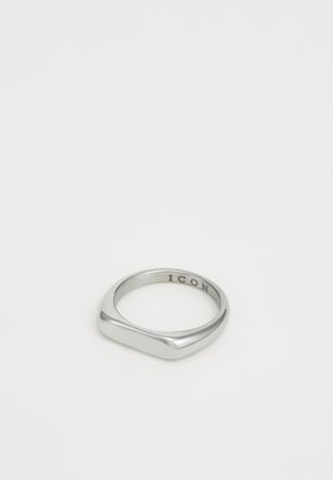 Sidabrinė antspauduota žiedas su plokščiu viršumi ir žodžiu "IKONA", išgraviruotu vidinėje juostos pusėje, prieš paprastą baltą foną.