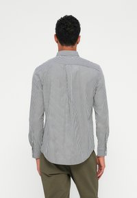 Striped skjorte i sort og hvit bomull med knapp-ned krage og lange ermer. Rundet hem og skraddersydd passform bak.