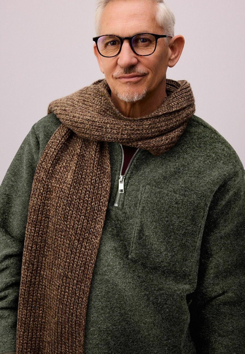 Dark green fleece pullover with a zip neck and front pocket, paired with a thick brown knitted scarf featuring a textured pattern.