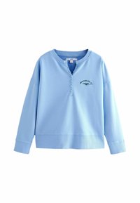 Chemise henley à manches longues bleu clair avec cinq boutons et l'inscription "New York City, NY Manhattan 1985" imprimée sur la poitrine gauche.