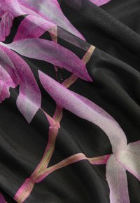 Áttetsző fekete textilemből készült, élénk rózsaszín virágmintával és finom zöld kiegészítőkkel, amely texturált, lebegő redőzést mutat.