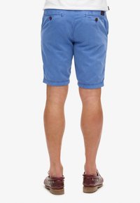 Shorts in cotone blu da uomo con vestibilità regolare, due tasche posteriori e chiusura con bottone. Rifiniti a metà coscia, texture liscia.