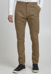 Kaki chinos med slim fit, laget av bomull. Har knappelukking, frontlommer og lett avsmalnede ben.